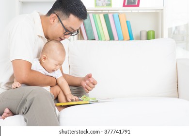 Asian Family Lifestyle At Home. Father And Child Reading Story Book On Sofa.