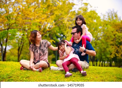 Asian family lying outdoors being playful and smiling, Outddor portrait