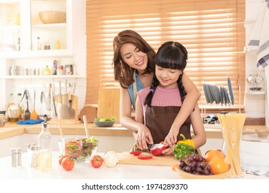 Asian family mom and child enjoy cooking salad together in kitchen room at home. - Powered by Shutterstock