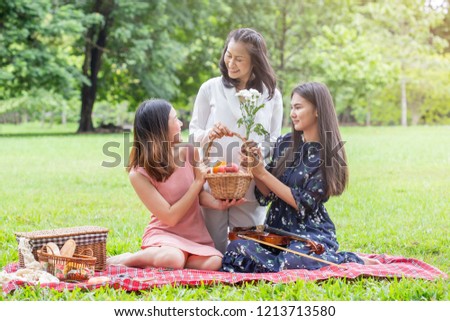 Asian family mom and daughter happy picnic with fruit basket in garden. Family and picnic concept.