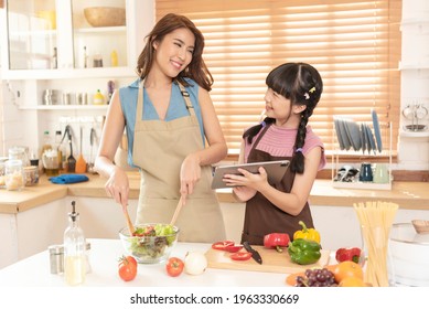 Asian Family, Mother And Daughter Enjoy Cooking Salad Together In Kitchen Room At Home.