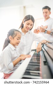 Asian family, Mother and daughter playing piano,Father playing guitar in family band at home, Concept for family relationship