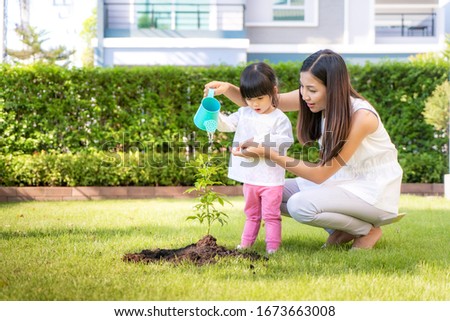 Asian family mother and kid daughter plant sapling tree and watering outdoors in nature spring for reduce global warming growth feature and take care nature earth. People kid girl in garden.

