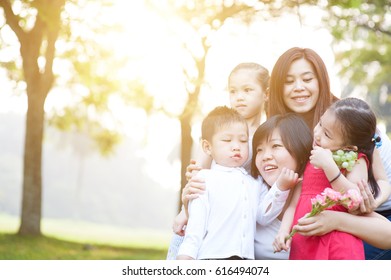 Asian Family At Nature Park, Parents And Children, Outdoor In Morning With Sun Flare.