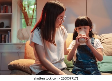 Asian Family At Night Time. Little Girl And Mom Drinking Milk With Smiling Before Bedding For Healthy. Mother Take Care Daughter. Happy Family At Home Concept.