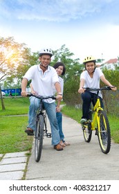 Asian Family On Cycle Ride In Countryside