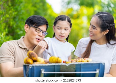 An Asian Family Of Parents And Daughters Camping With BBQ Tires. In The Front Yard Outside The House Together Happily