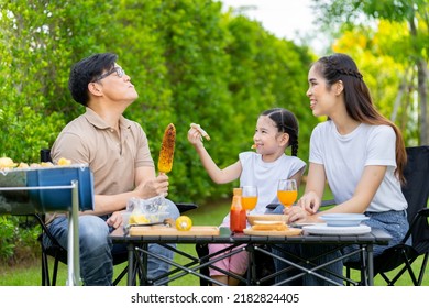 An Asian Family Of Parents And Daughters Camping With BBQ Tires. In The Front Yard Outside The House Together Happily