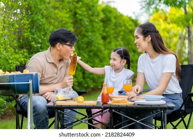 An Asian Family Of Parents And Daughters Camping With BBQ Tires. In The Front Yard Outside The House Together Happily