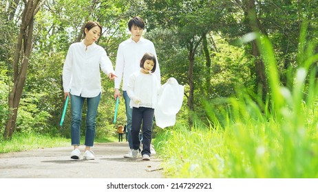 Asian Family Picking Up Trash In The Forest. Litter Cleanup Activities. Environment Protection. Recycling.