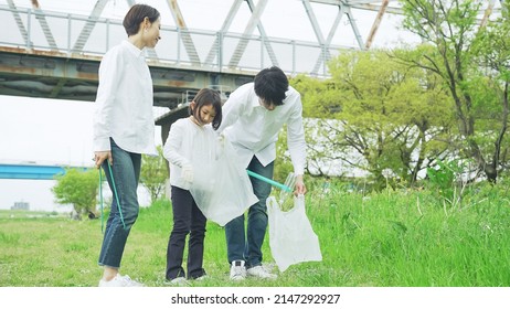 Asian Family Picking Up Trash In The Forest. Litter Cleanup Activities. Environment Protection. Recycling.