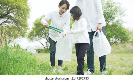 Asian Family Picking Up Trash In The Forest. Litter Cleanup Activities. Environment Protection. Recycling.