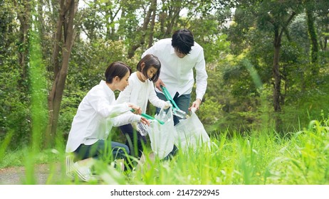 Asian family picking up trash in the forest. Litter cleanup activities. Environment protection. Recycling.