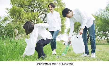 Asian Family Picking Up Trash In The Forest. Litter Cleanup Activities. Environment Protection. Recycling.