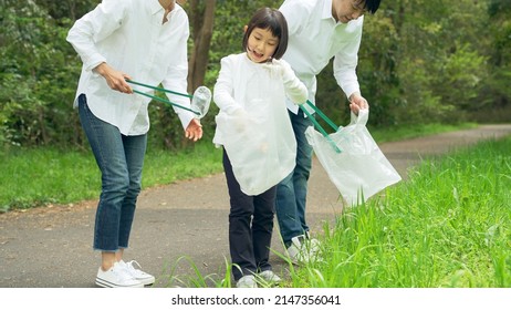 Asian Family Picking Up Trash In The Forest. Litter Cleanup Activities. Environment Protection. Recycling.