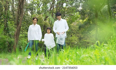 Asian Family Picking Up Trash In The Forest. Litter Cleanup Activities. Environment Protection. Recycling.