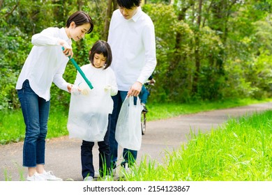 Asian Family Picking Up Trash In The Forest. Litter Cleanup Activities. Environment Protection. Recycling.