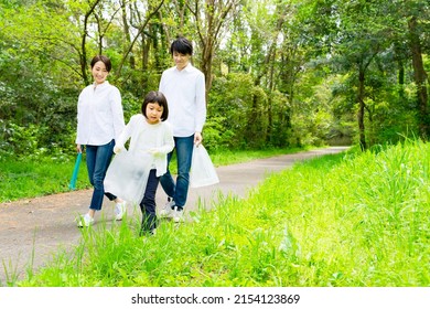 Asian Family Picking Up Trash In The Forest. Litter Cleanup Activities. Environment Protection. Recycling.