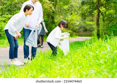 Asian Family Picking Up Trash In The Forest. Litter Cleanup Activities. Environment Protection. Recycling.