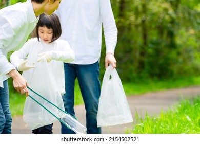 Asian Family Picking Up Trash In The Forest. Litter Cleanup Activities. Environment Protection. Recycling.