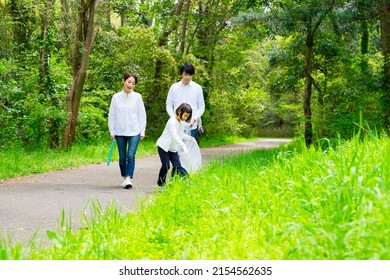 Asian Family Picking Up Trash In The Forest. Litter Cleanup Activities. Environment Protection. Recycling.