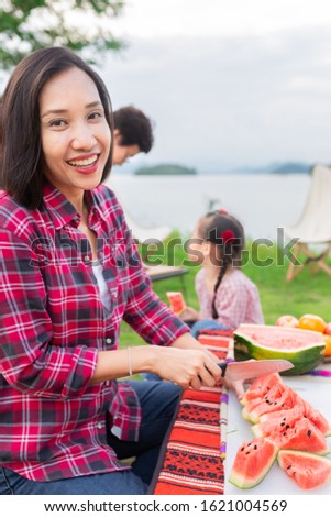 asian family picnic and camping in forest, asian female use knife slice watermelon, they relax and feeling happy, happiness family activity