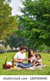 Asian Family Picnic In A Garden In A Public Park. Asian Family, Outdoor Activity, Summer Or Happy Family Concept