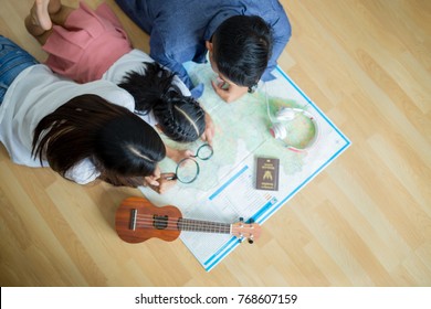 Asian Family Is Planning A Travel Trip.They're Looking At A World Map