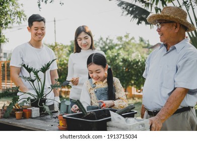 Asian Family Planting Tree In Garden At Home. Parent With Kid And Grandfather Lifestyle.