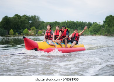 Asian Family Play Banana Boat In Tropical Resort In Thailand.