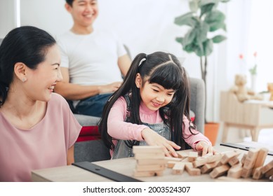 Asian Family Playing Board Game With Wooden Tower Together At Home.