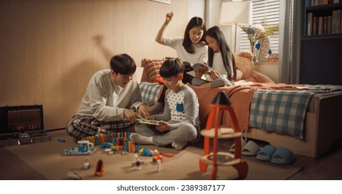 Asian Family Playing with Kids in Children's Bedroom. South Korean Parents Spending Entertaining Time Together with Their Adorable Daughter and Son. Boy Using a Tablet Computer, Girl Reading a Book - Powered by Shutterstock