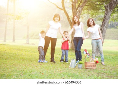 Asian Family Playing At Nature Park, Parents And Children, Outdoor In Morning With Sun Flare.