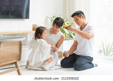 Asian Family Playing With Their Daughter With Toys In The Living Room Of Their Home	