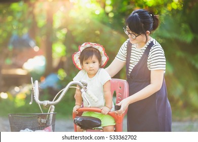 Asian family portrait of mother and her kid try to ride a bicycle.