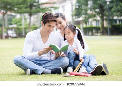 Asian Family Reading Book Together At Outdoor Place. People Lifestyle Concept.