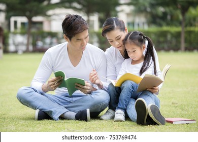 Asian Family Reading Book Together At Outdoor Place. People Lifestyle Concept.