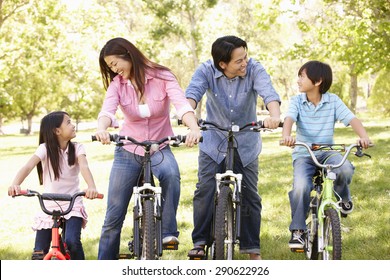 Asian Family Riding Bikes In Park