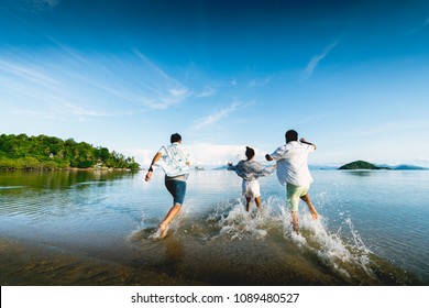 Asian Family Running On Background Of Sunset Beach And Sea