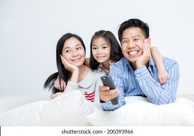 Asian Family Sitting On Sofa Watching TV Together