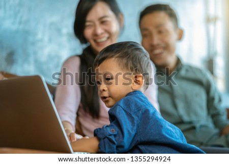 Asian family with son are looking the cartoon via technology laptop and playing together when living in loft house for Self learning or home school,Family home school concept