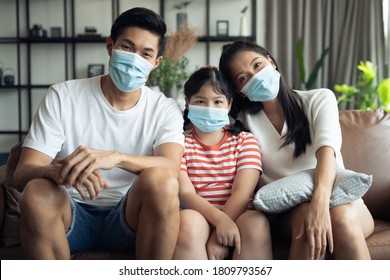 Asian Family Spending Time Together At Home While Wearing Face Mask. Precaution To Prevent Coronavirus By Wearing Protective Mask.