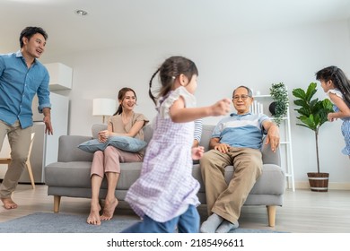 Asian family spending time together on holiday in living room at home. Attractive happy parents, father play with young little two kid girl daughter run around sofa in house. Activity relationship. - Shutterstock ID 2185496611