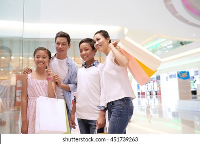 Asian Family Standing In Front Of Shopping Window