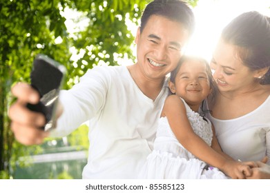 Asian Family Taking Photographs In The Park