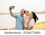 Asian family taking selfie picture with smartphone outdoor nature park, Happy smile father mother and child daughter taking photo with mobile phone together, Tourist lifestyle people leisure activity