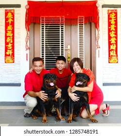 Asian Family And Their Dogs With Chinese New Year Decoration Background. Chinese Characters In The Photo Means 