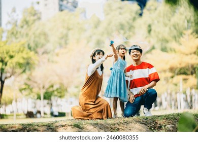 An Asian family of three heads to the park for a picnic, indulging in games and blowing bubbles together.  - Powered by Shutterstock