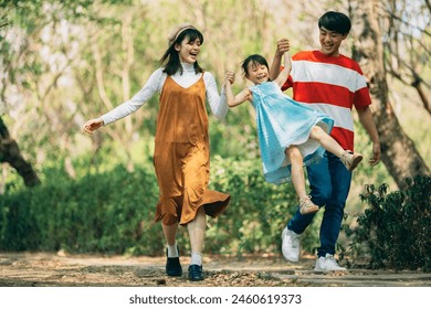 An Asian family of three heads to the park for a picnic, indulging in games and blowing bubbles together.  - Powered by Shutterstock