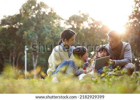 asian family with two children relaxing outdoors in city park